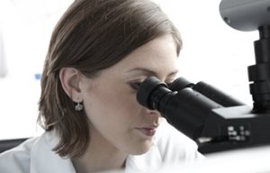 Wissenschaftlerin schaut durch ein Mikroskop.