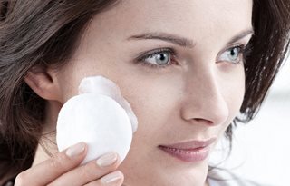 Frau trägt mit Wattepad Reinigungsmilch auf.