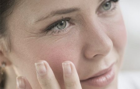 Frau berührt ihr Gesicht mit der Hand.