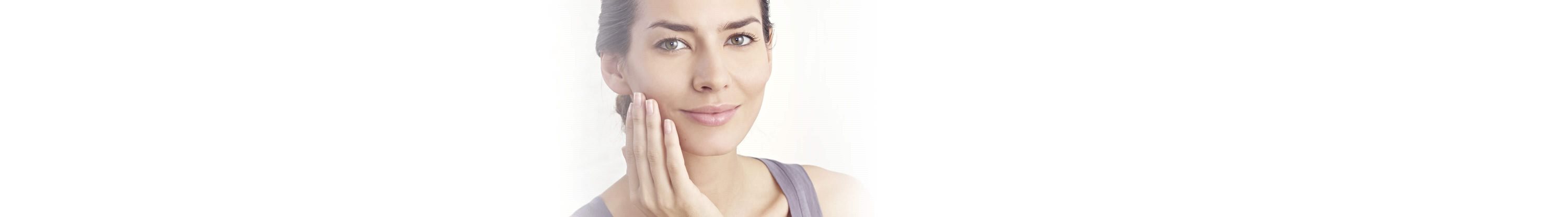 Frau fasst sich ins Gesicht