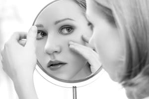 Junge Frau trägt Eucerin DermoPURIFYER Cover Stick auf.